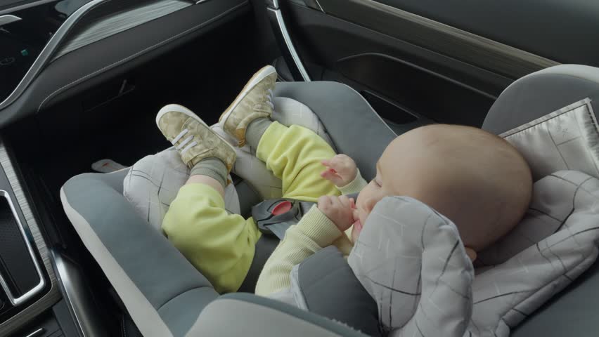 Baby in car seat in modern car interior. Daylight through window during short road trip. Secure harness. concept of infant safety in a child seat. peaceful atmosphere and gentle motion during drive