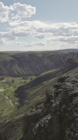 Man walking over on a rocky ledge overlooking canyon vast mountain valley in nature in Parque Patagonia. Santa Cruz, Argentina