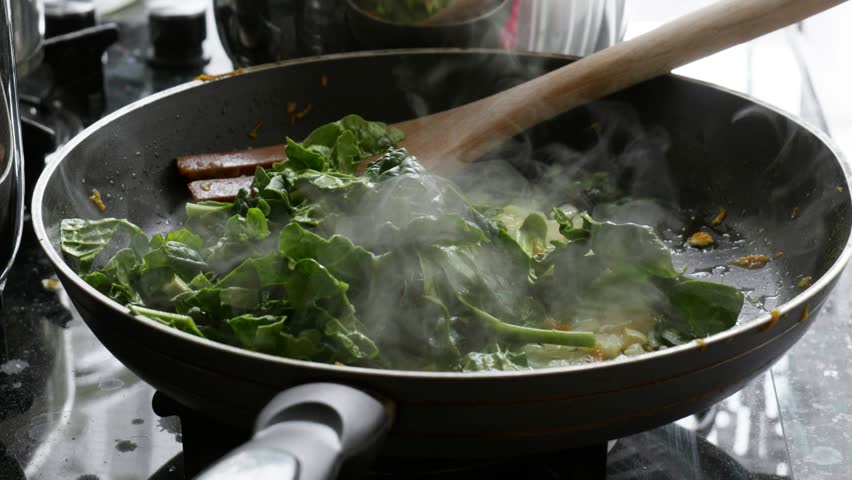 Sauteing Fresh Spinach Leaves in Pan with Rising Steam Slow Motion