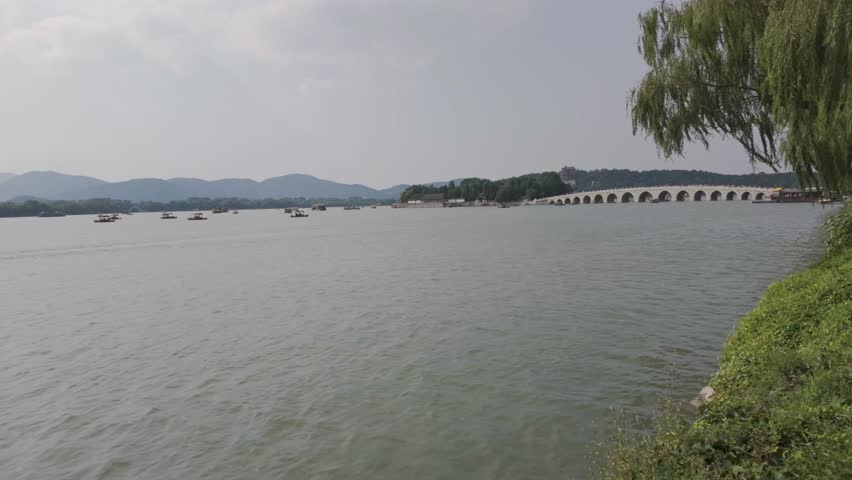Wide lake landscape with distant shoreline and trees at Summer Palace Beijing China, pan left