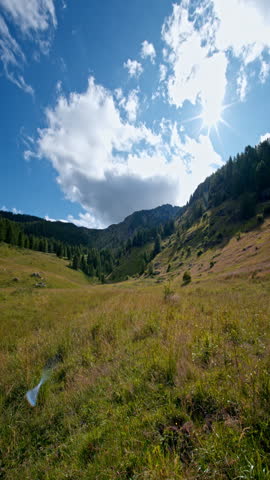 Sunny day in mountain valley with blue sky and fluffy clouds