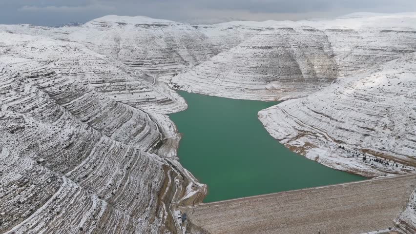 Beautiful contrast between turquoise water and snow-covered dam structure at Chabrouh Dam in winter.