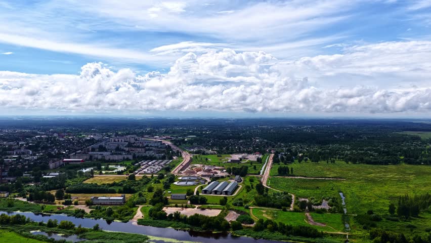 Aerial view of a river, town, and green fields under a cloudy sky