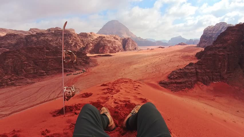 Rider pov Sand boarding from red dune Wadi Rum Jordan, traveler POV with board, desert adventure freedom concept. Wadi rum tours and Sand boarding, hiking, wandering outdoors activities