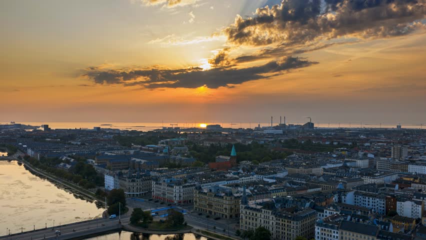 Copenhagen aerial sunrise over city skyline with dramatic orange clouds moving across harbor waters.