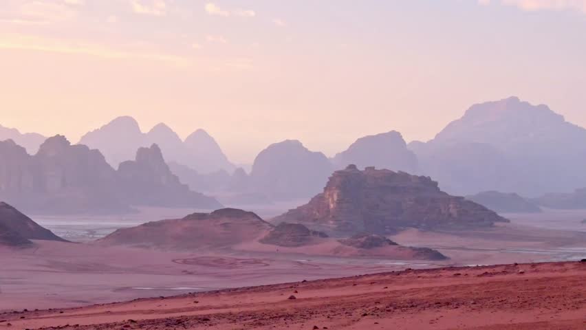 Colorful sunset changing light over the red sandstone mountains of Wadi Rum, Jordan. The desert sky turns soft pink and purple during twilight in the Valley of the Moon