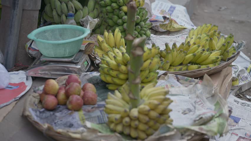 Close up of yellow bananas and red apples on newspaper at a traditional street market in India. Ideal for travel documentaries, food industry, and cultural content.