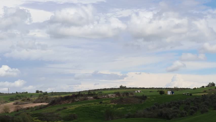 Scenic Countryside Landscape Under Cloudy Sky, Peaceful countryside view of rolling hills and trees under moving clouds.