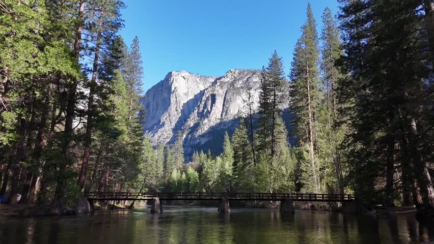 This 4K video captures Yosemite National Park in California. The visual documents the 3,000-foot granite face of El Capitan and the 2,425-foot Yosemite Falls. The composition illustrates the Merced River during the spring snowmelt season, documenting Sierra Nevada geomorphology and high-volume waterfall hydrology for nature, science, and editorial media.