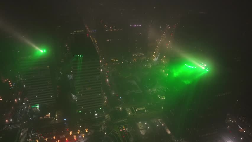 Aerial night view of downtown Philadelphia glowing in green lights during winter snowfall, with traffic below and city streets illuminated in support of Eagles. Vibrant atmosphere in USA. Approaching.