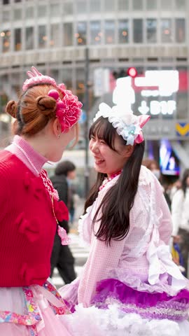 Two young women in vibrant Decora fashion laugh and cheer at Tokyo