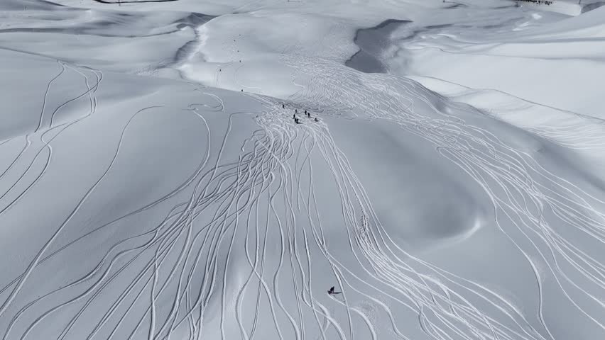 Freeride skiers climbing and descending Bidara peak in Gudauri on deep fresh powder snow, winter adventure in Georgia mountains. Backcountry freeride and skiing untouched powder in snowy mountains.