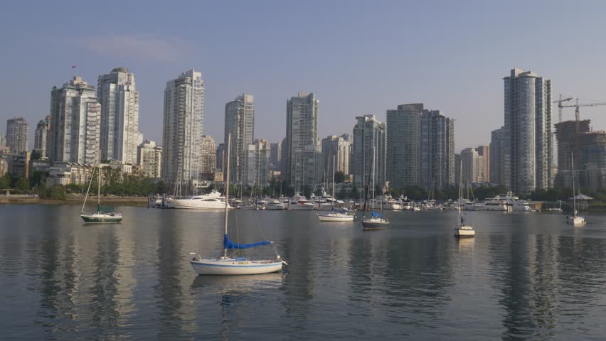 Yaletown skyline in Vancouver with sailboats floating on calm False Creek water and modern glass high rises under clear sky creating scenic urban waterfront view