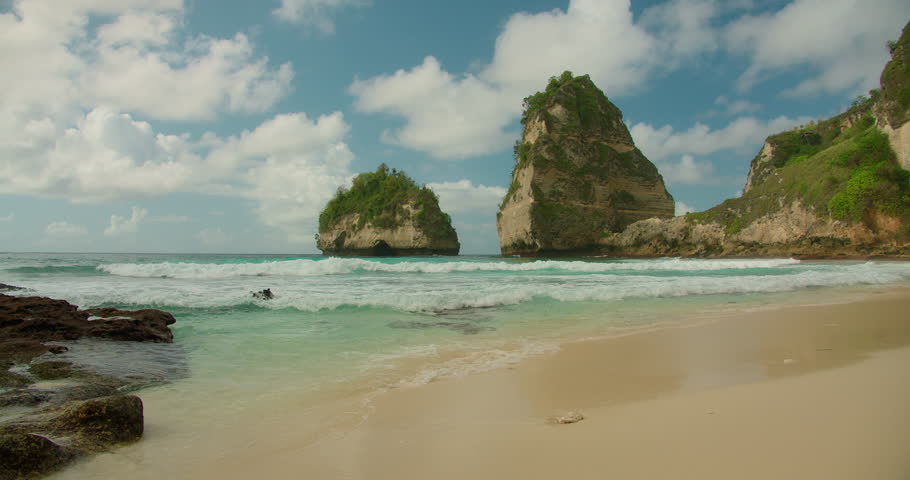 Gentle waves washing onto a pristine beach surrounded by jagged coastal formations