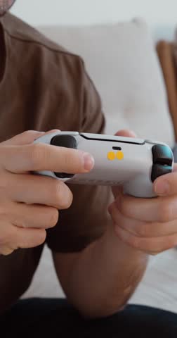Close-up of hands holding a game controller while playing video games at home. Modern gaming and entertainment lifestyle.