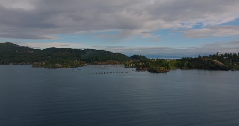 Small forested shoreline and low islands surrounded by still lake water beneath a cloudy sky forming a tranquil natural panorama, Flathead Lake Montana USA