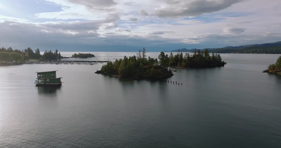 Tree covered islands rising from calm blue lake water surrounded by house boat and marina docks, Flathead Lake Montana USA