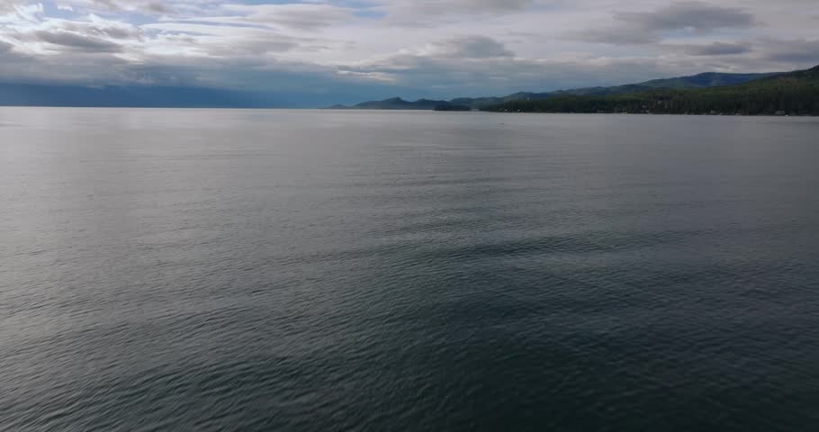 Soft ripples moving across wide open lake water beneath layered clouds creating a calm and expansive natural scene, Flathead Lake Montana USA