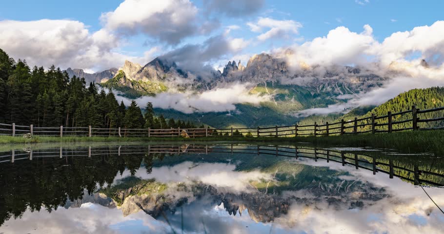 Santner Pass lake clearly reflecting mountains, clouds, and trees under a blue sky. timelapse