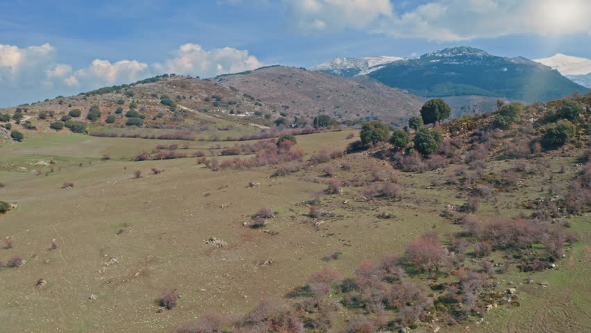 Wonderful Sierra Nevada Plateau in Andalusia snow capped peaks mountains ancient pastures traces moorish agriculture winding trails bright blue sky over Spanish nature aerial view travel destination