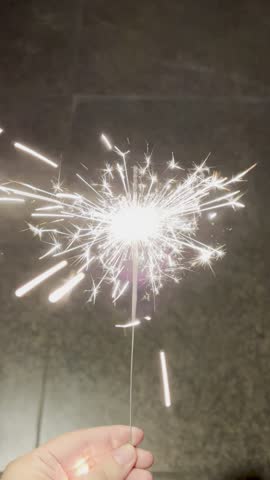 Point of view hand holding a lit sparkler in celebration