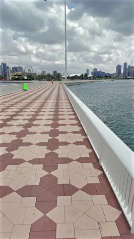 The national flag of the UAE waves over Sharjah during a cloudy day.
