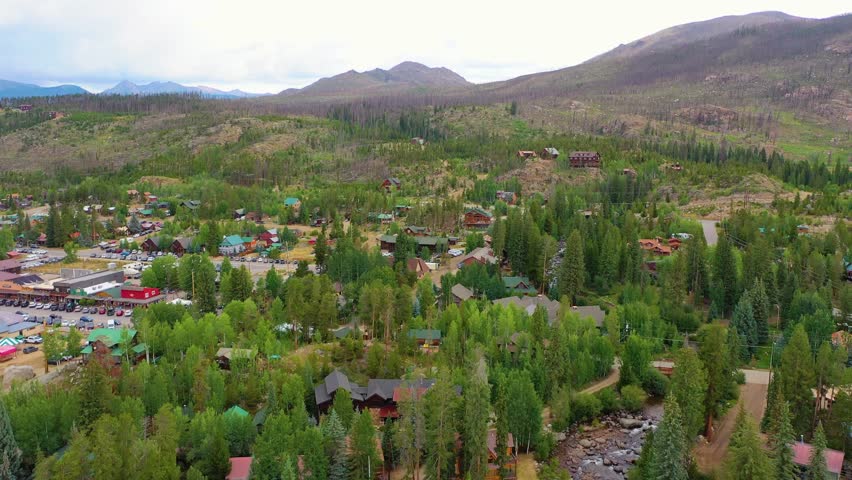 Aerial view of Coeur d Alene Idaho with hillside homes, forested terrain, winding roads, and dramatic mountain scenery surrounding a scenic alpine community