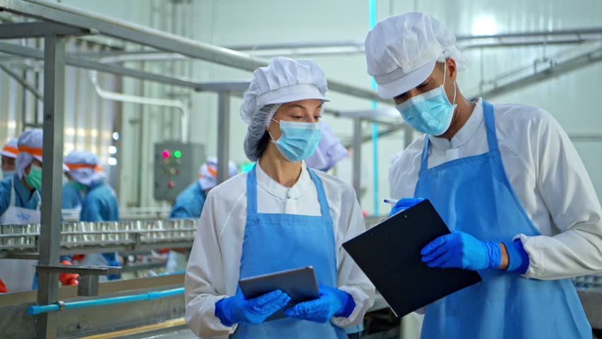 Both of quality control officer inspecting raw fish materials in a seafood processing factory before entering the production line