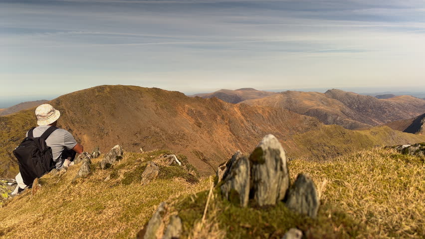 Male Hiker Looking at Crib Goch Ridge and Snowdon Mountain Massif, Snowdonia National Park, North Wales, UK