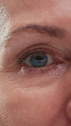 Close up portrait: old eye female, macro. Beauty senior woman with grey hair open eyes. Retired lady looks up, wrinkles skin. Eyesight or vision. Grandma lifts her eyelids, looking and blinking