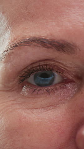 Close up portrait: old eye female, macro. Beauty senior woman with grey hair open eyes. Retired lady looks up, wrinkles skin. Eyesight or vision. Grandma lifts her eyelids, looking and blinking