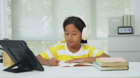 Elementary school girl wireless headphones and watching an interactive online lesson on a digital tablet. Concept for happy e-learning, distance education, and modern edtech. - Powered by Shutterstock - Get 15% off with code: PIKWIZARD15