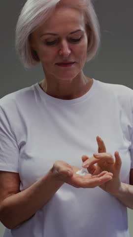 Close up portrait: old woman, taking face cream for older skin with fingertip. Advertising of antiwrinkle antiaging whitening rejuvenation uv protection senior female in menopause treatment. Wrinkles