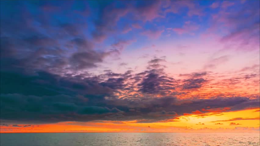 A breathtaking view of the vibrant sunset sky reflecting over the calm ocean waters at dusk.