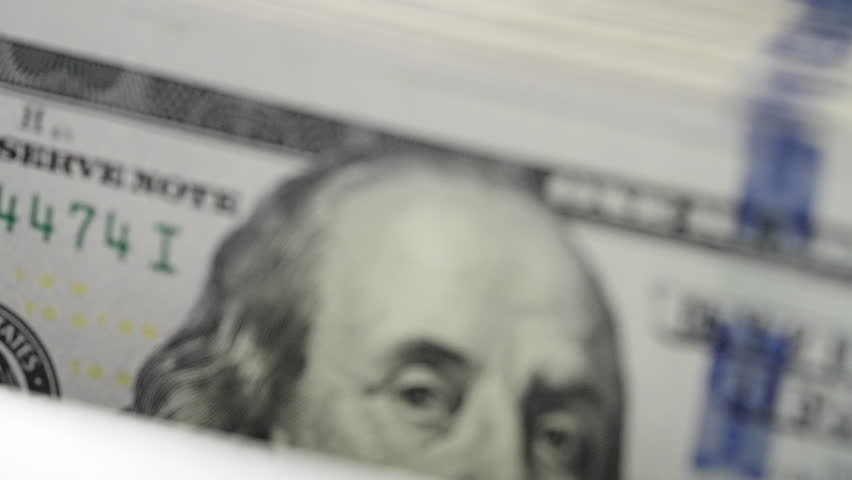 Close up automatic currency counter machine processing stack hundred dollar bills. High speed banking equipment counting American cash money. Financial technology business accounting wealth management