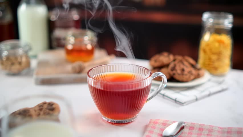 Hot tea in glass cup with steam on kitchen table