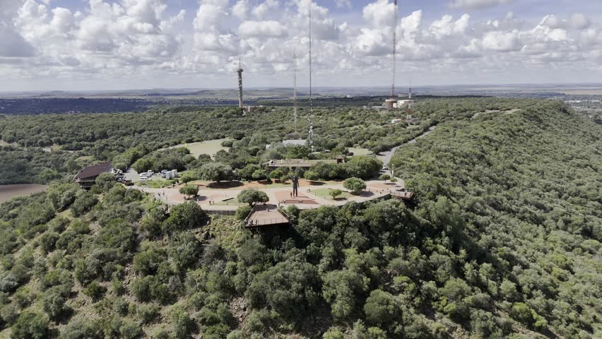 Drone does 360 in wide shot of Mandela statue atop Naval Hill on partially cloudy afternoon in Bloemfontein, South Africa