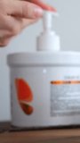 Closeup pump moisturizer jar on wood, soft natural light and shallow depth of field showing white pump container and small amber jar, neutral gray background, clear product label blur for commercial - Powered by Shutterstock - Get 15% off with code: PIKWIZARD15