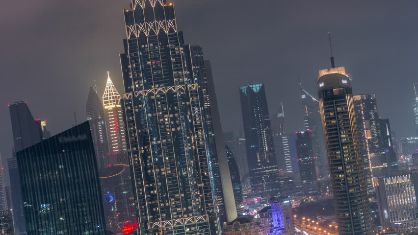 Illuminated modern skyscrapers, office towers, and hotels in the Dubai International Financial Centre DIFC. Aerial night view showing downtown traffic in time-lapse.