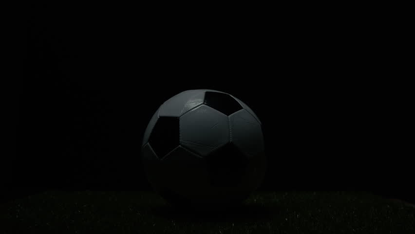 Lights flashing illuminate a football ball in the stadium at night on the meadow