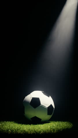 A spotlight searches for a soccer ball rolling on the grass, copy space