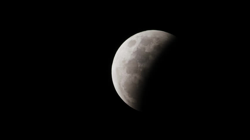 A first quarter moon at night with clear skies and half of the moon covered in light and the other in darkness.
