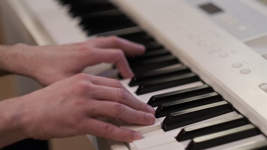 Close-up of hands playing a digital piano keyboard in a natural indoor setting. Ideal for music, creativity, performance and background video use.