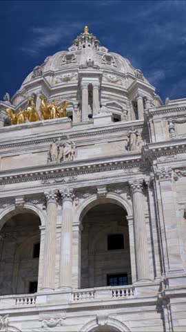 The State Capitol in St Paul shows its detailed architecture against a blue sky with clouds.