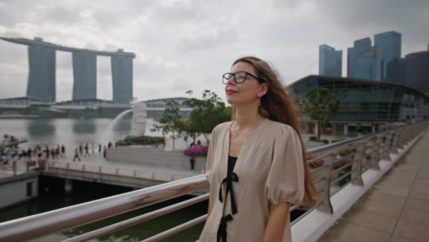 Female tourist exploring Singapore city and enjoying panoramic bay view with iconic modern buildings