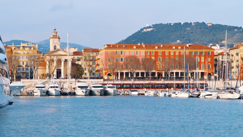 Scenic harbor view with yachts and historic buildings along the waterfront in Nice France.