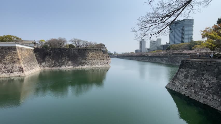 Ancient Stone Fortifications with Moat and Modern Cityscape Beyond