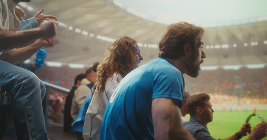 Close-up of Joyful Soccer Supporters in a Packed Stadium During a Professional International League Match, With a Smiling Young Black Couple in Clapping as the Crowd Celebrates Victory.