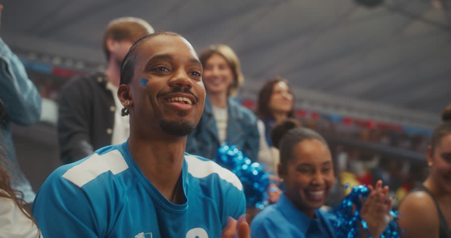 Close-up of Joyful Soccer Supporters in a Packed Stadium During a Professional International League Match, With a Smiling Young Black Couple in Clapping as the Crowd Celebrates Victory.