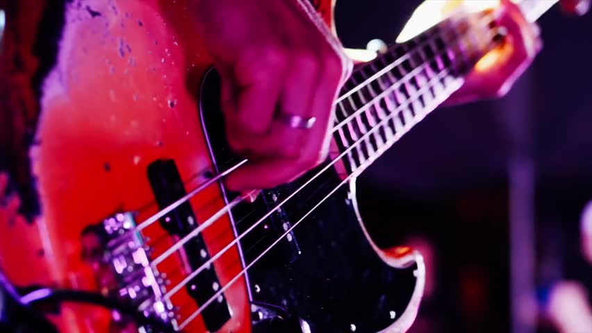 Guitarist playing electric guitar on a dark concert stage in closeup, highlighting live music performance, energy, and artistic expression.